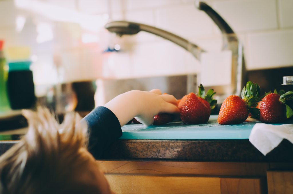 toddler reaches for strawberry on counter