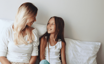 mother and daughter sit on bed having conversation