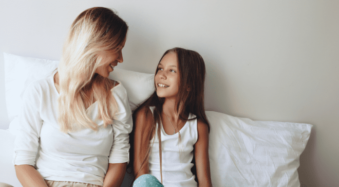mother and daughter sit on bed having conversation
