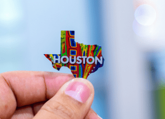 hand holding a tiny pin of shape of Texas with Houston