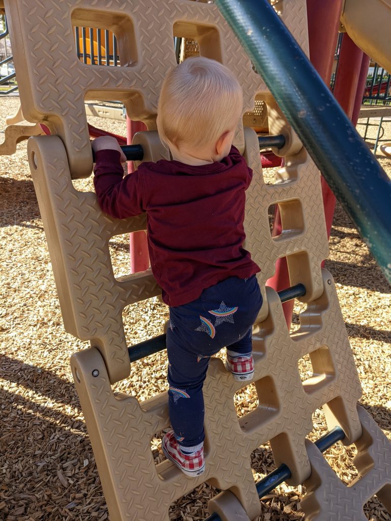 toddler climbing on play structure at park 