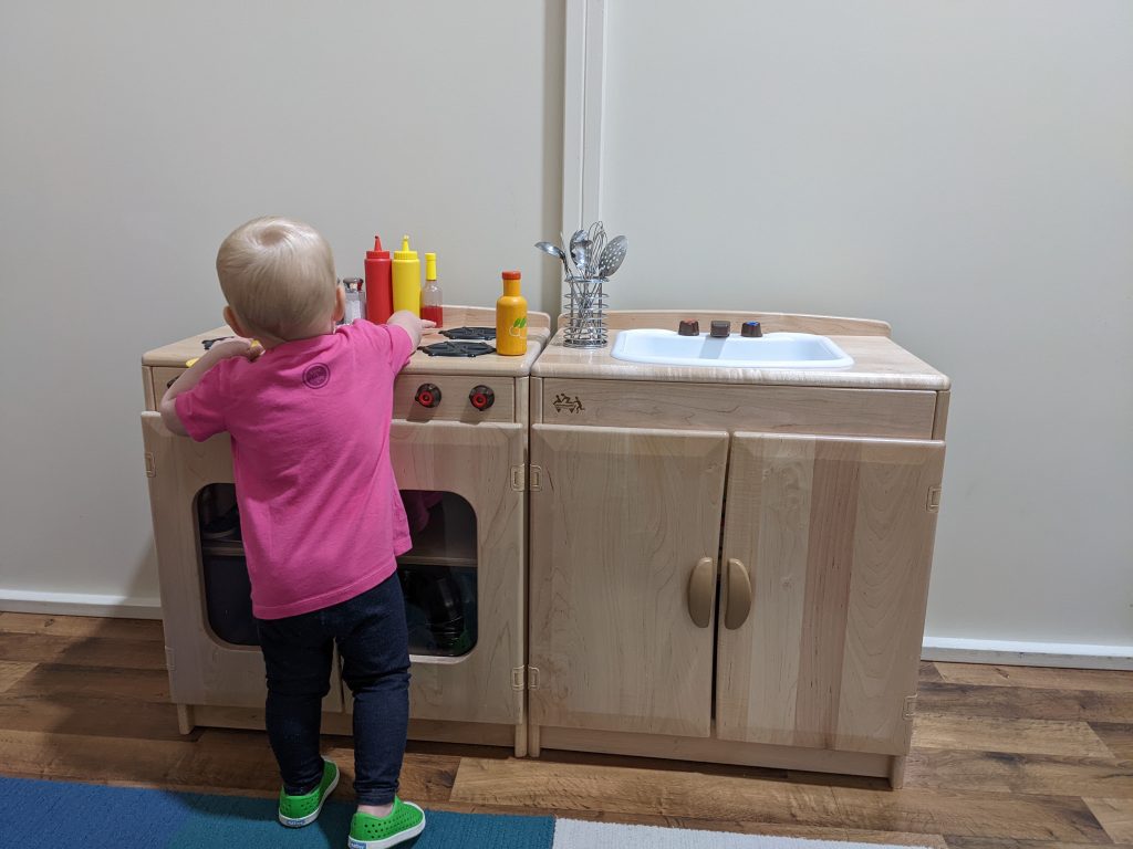 baby playing with play kitchen