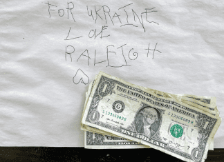 A note in a child's writing with the text: For Ukraine love Raleigh. Four 1 dollar bills are on top of the note.