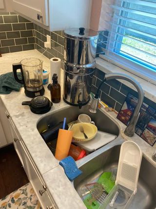 sink full of dishes and cluttered countertop