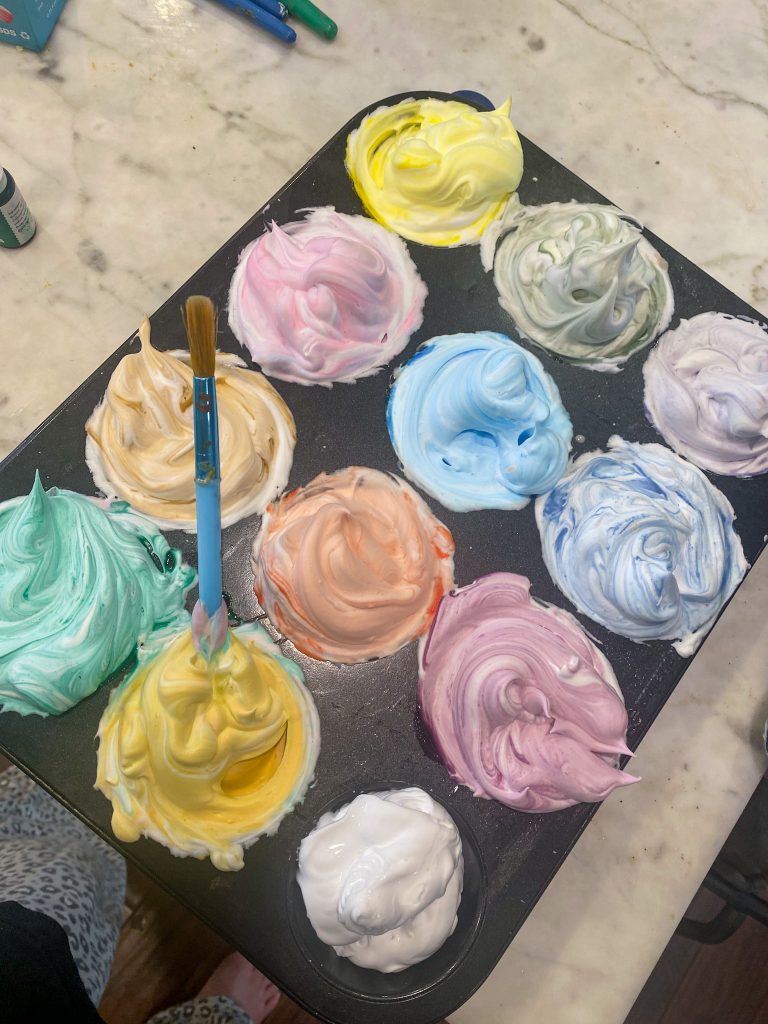 muffin tin of colored shaving cream and paintbrush