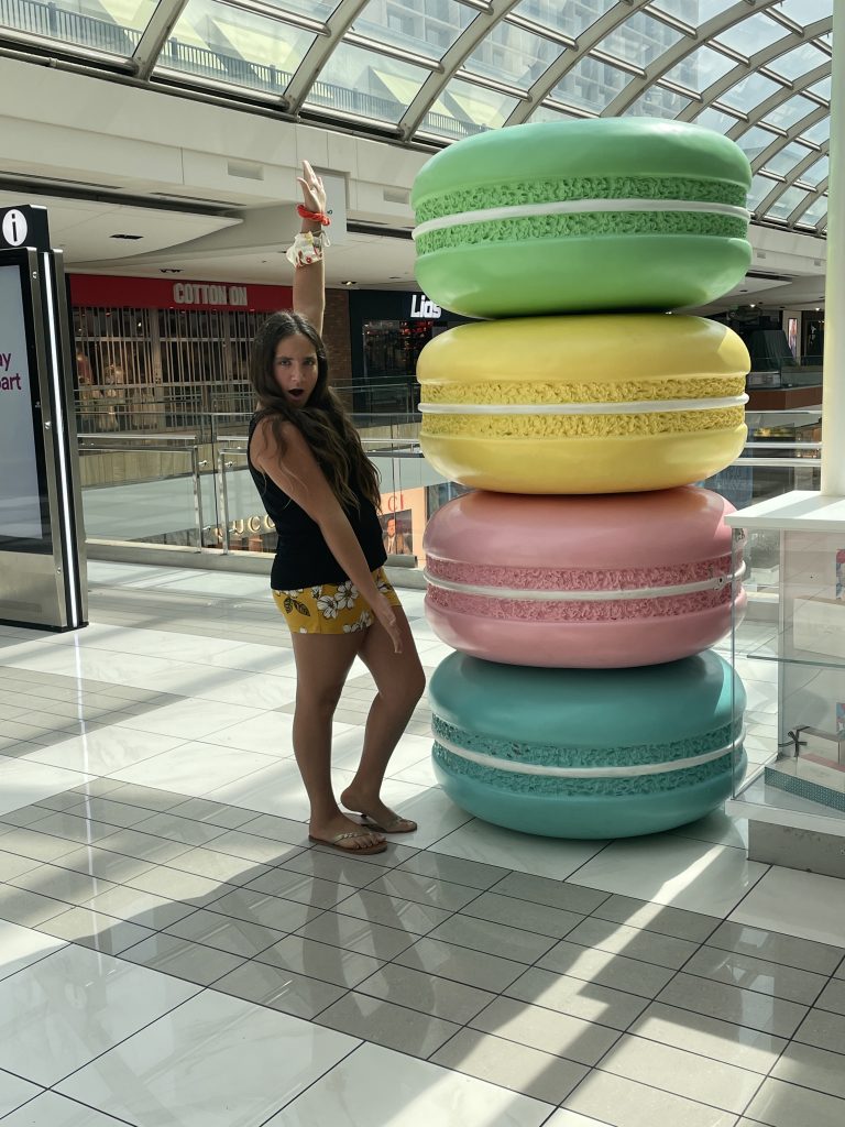 teenager poses next to a statue of stacked macarons
