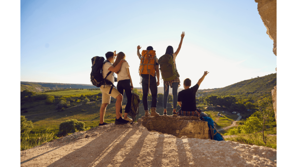 People on family vacation standing on top of mountain with hands raised