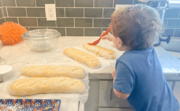 toddler buttering bread on counter