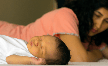woman suffering from postpartum depression lays next to newborn