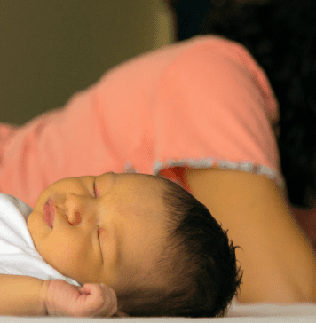 woman suffering from postpartum depression lays next to newborn