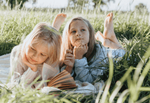 young girls laying in grass reading summer books