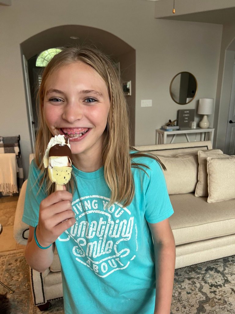 girl grins as she eats an ice cream bar