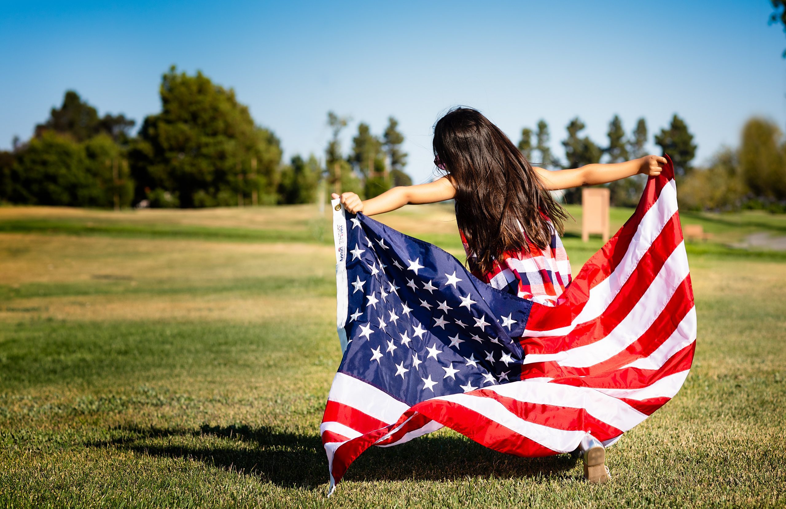 girl with American flag in grassy field