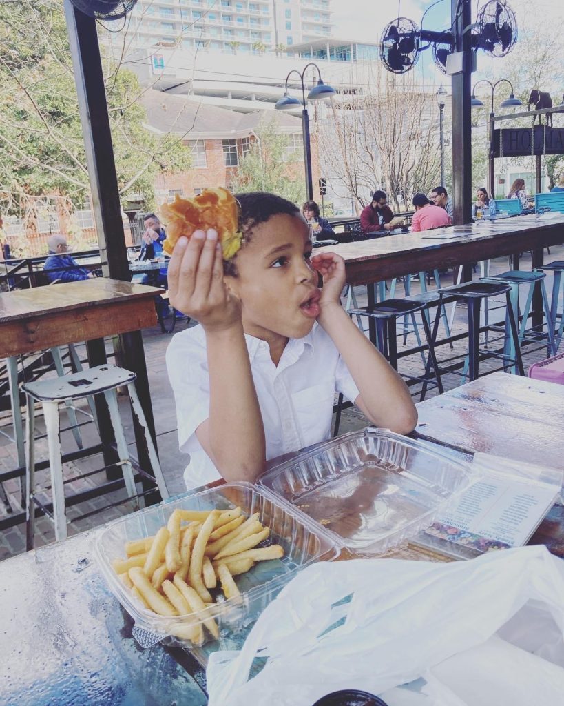 child eats burger and fries on patio of restaurant