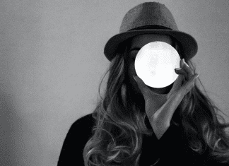 woman holds up glowing white circle over her face