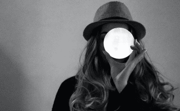 woman holds up glowing white circle over her face