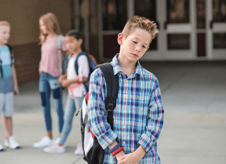 tween boy with changing friendships standing apart from group of kids looking dejected