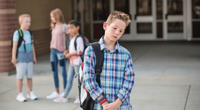 tween boy with changing friendships standing apart from group of kids looking dejected