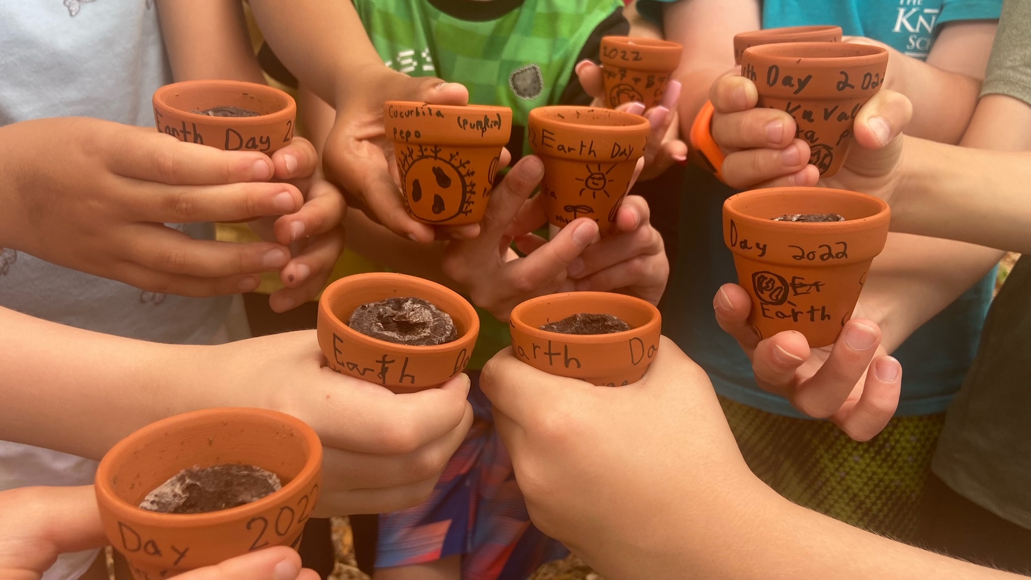 hands of children holding small flower pots