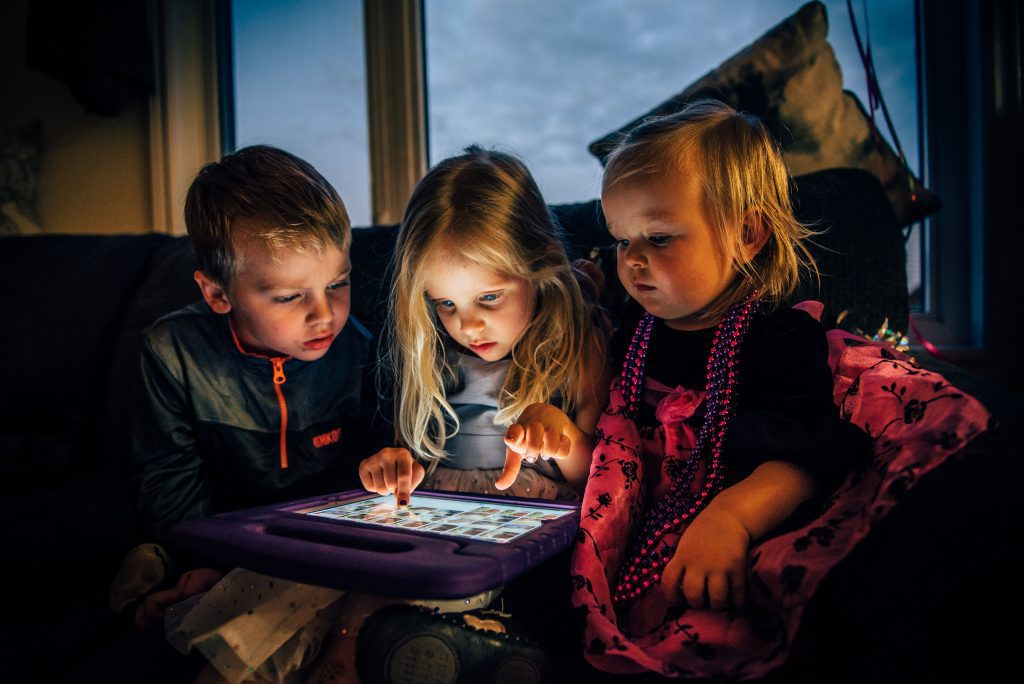 three young kids have screen time on tablet