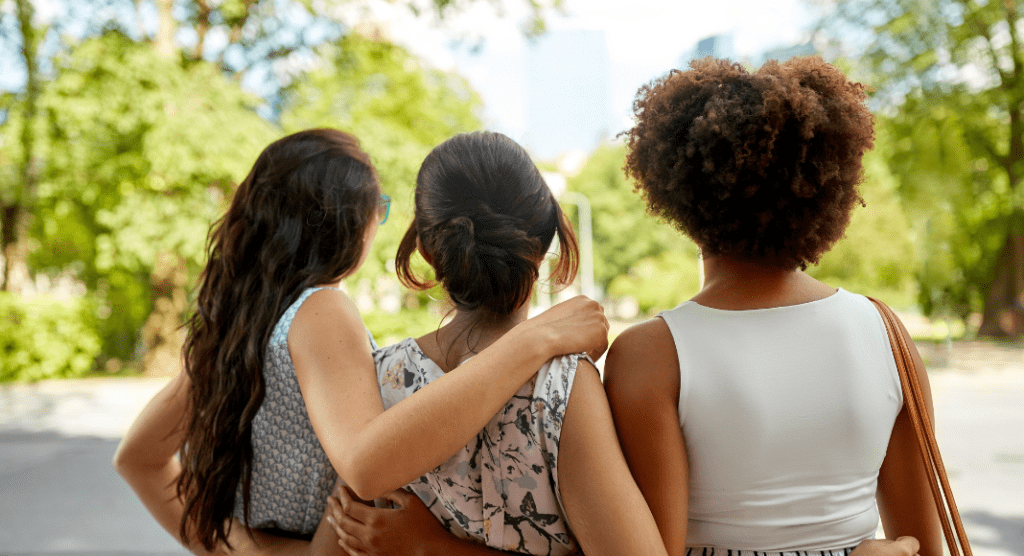 backs of 3 women with arms around shoulders