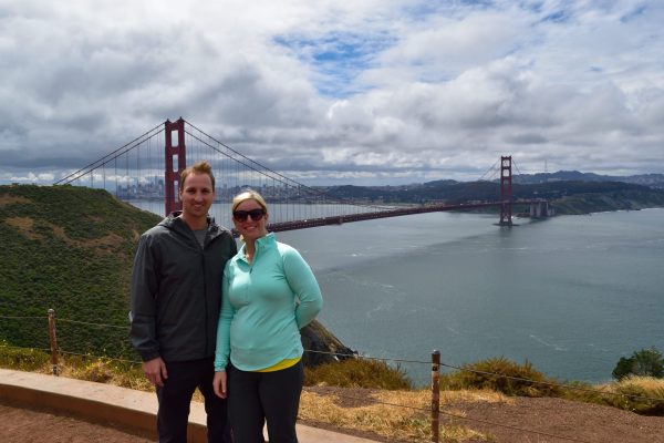 couple stands in front of Golden Gate Bridge
