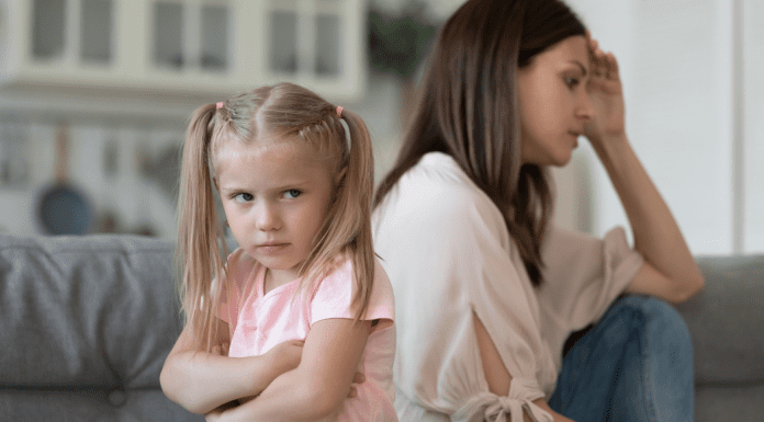 little girl with arms crossed turns back on exhausted mother