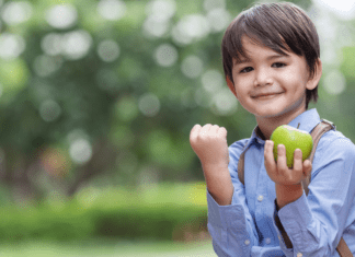 boy with backpack holds apple