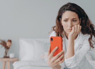 woman feeling pressure to post on social media stares at phone