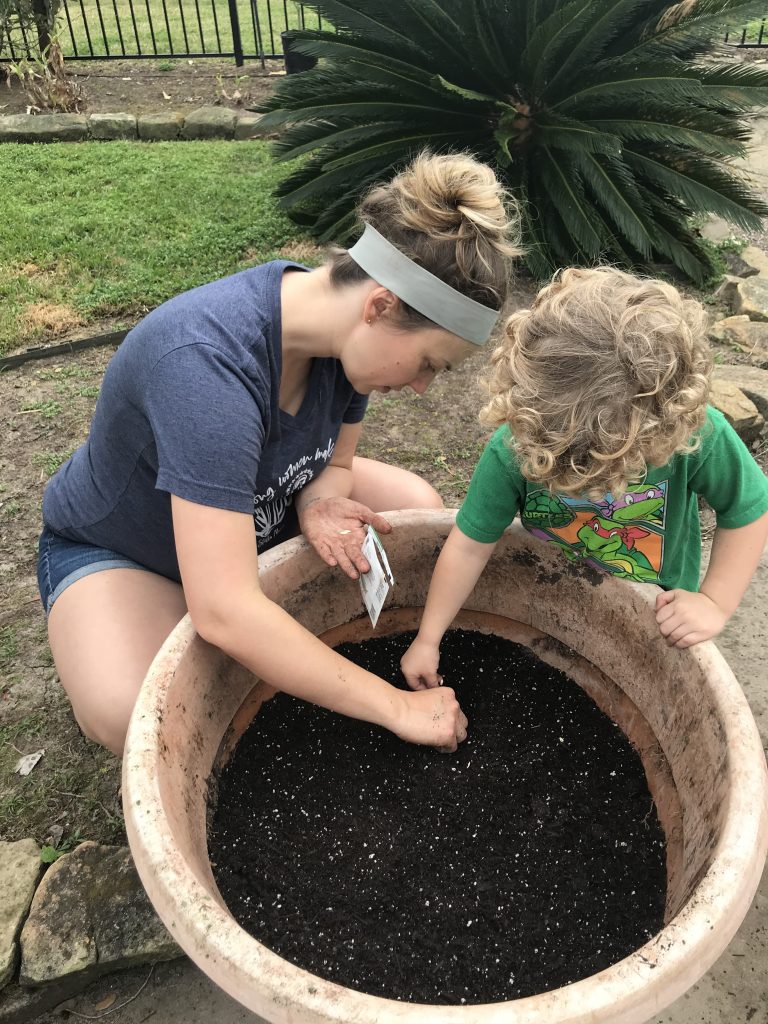 mom and young son plant seeds in planter