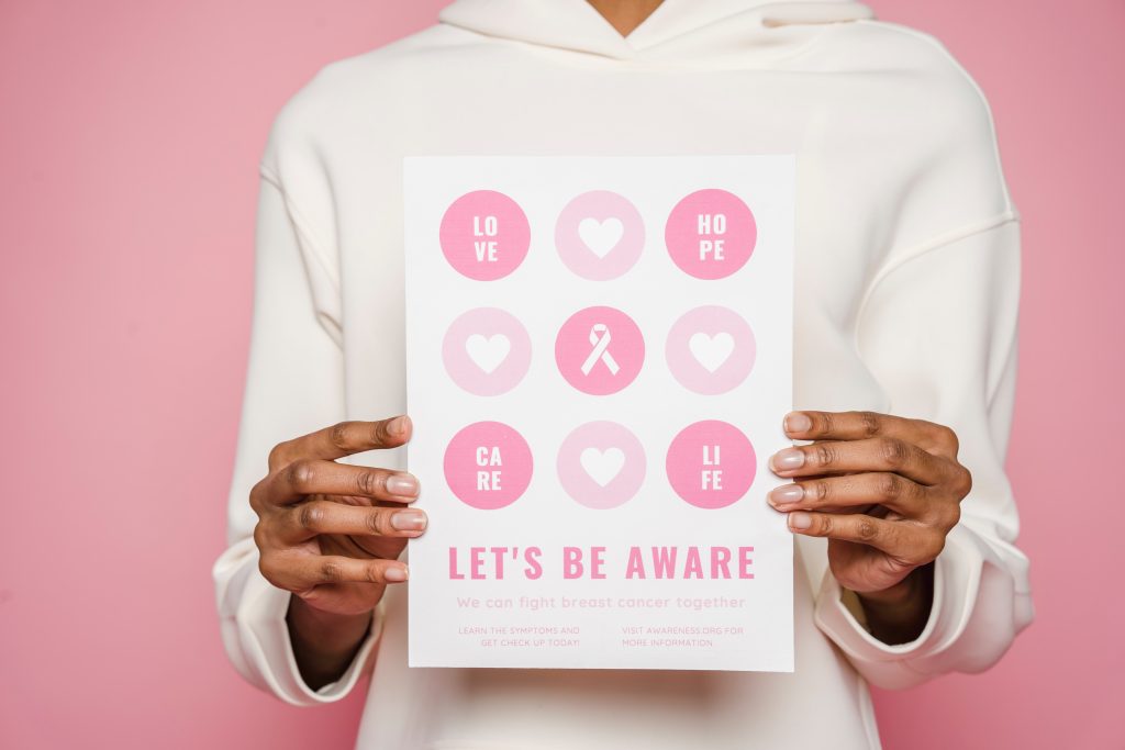 woman holds up breast cancer awareness card