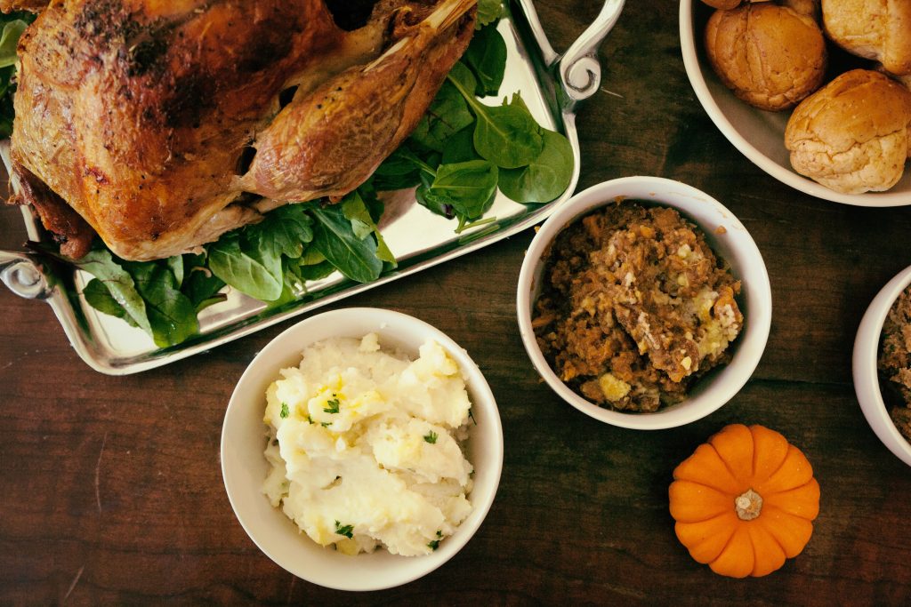 turkey, stuffing, mashed potatoes, and rolls on a table