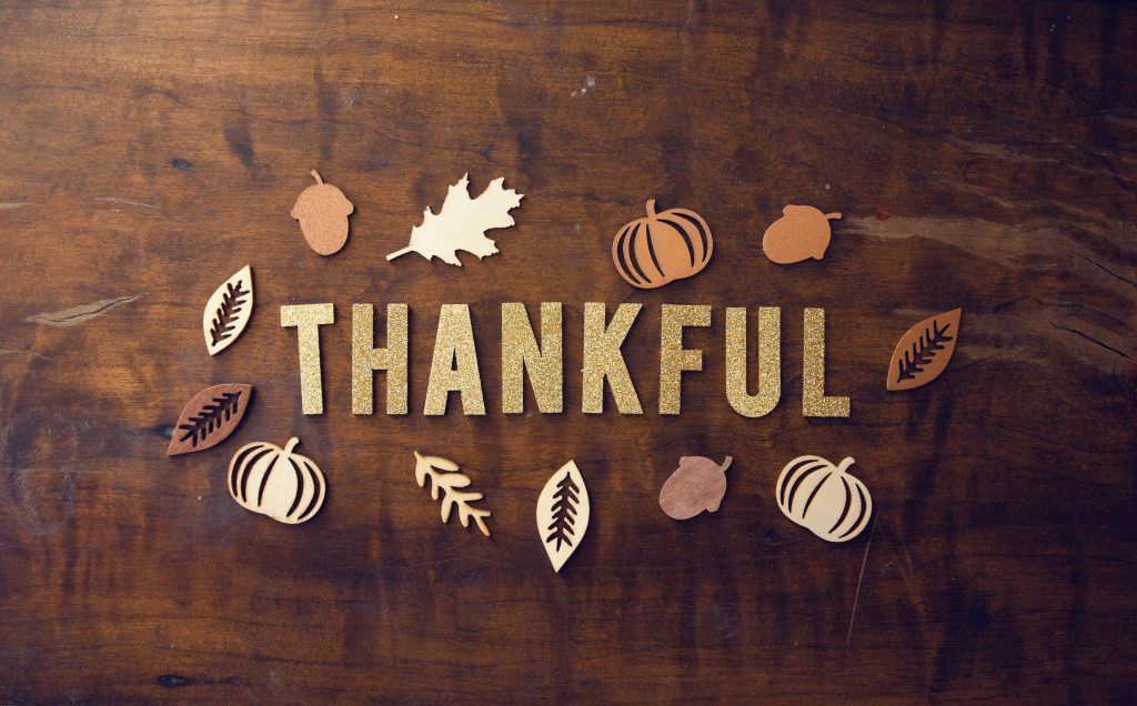 wood background with cutout letters and fall shapes that say Thankful