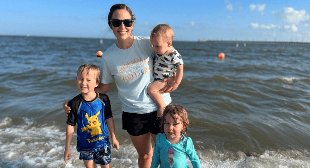 mother stands with three kids in ocean