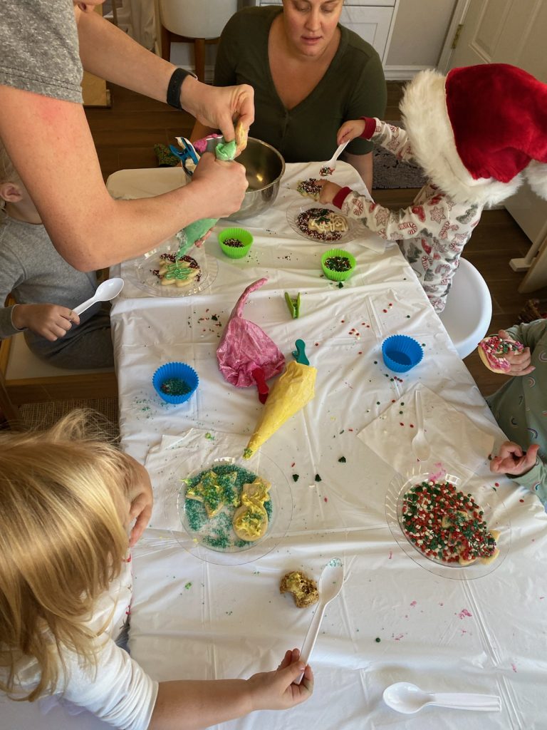 kids and adults gathered at a table decorating cookies