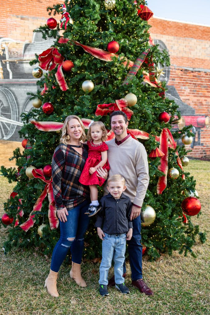 family poses by Christmas tree