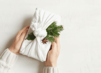 hands holding gift wrapped in cloth with sprig sticking out