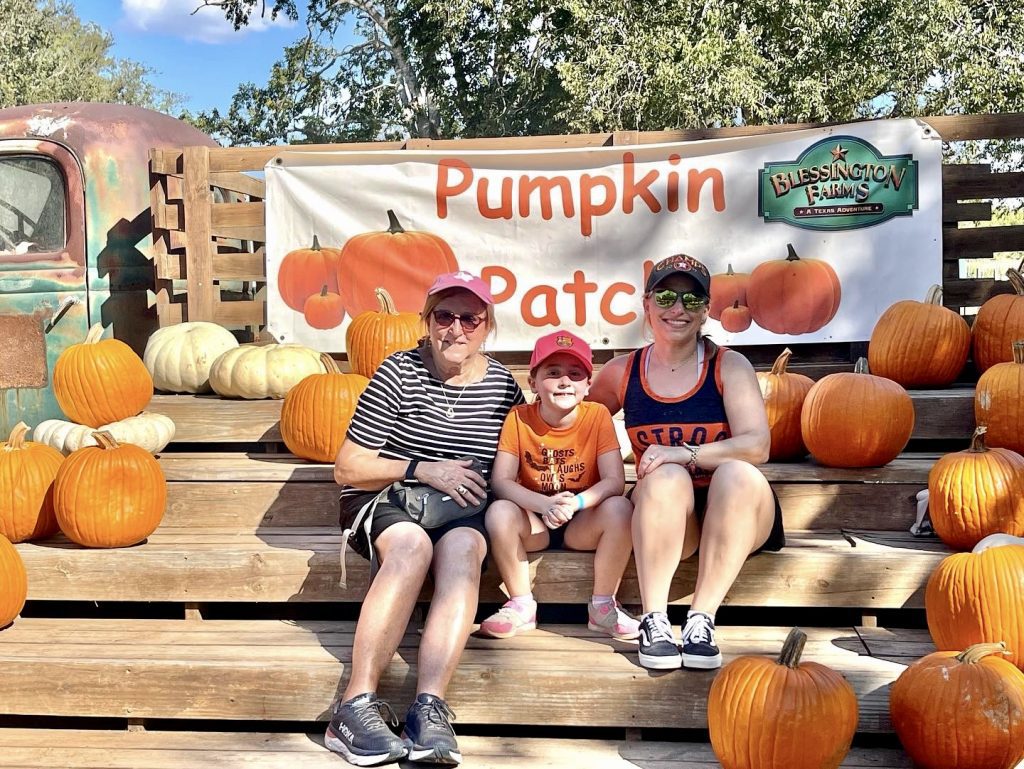 family sits in pumpkin patch