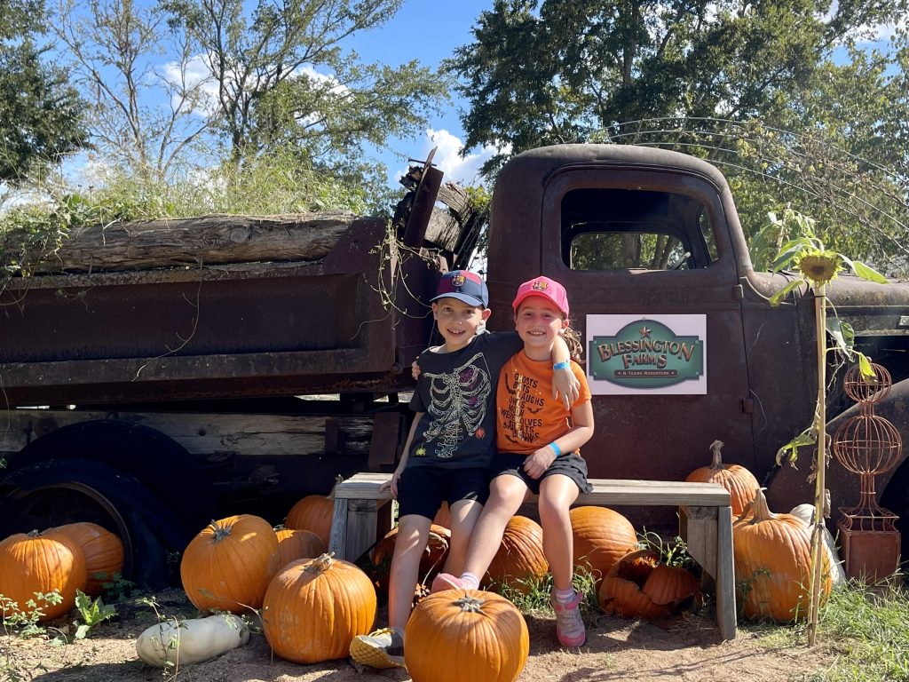 kids sit on old truck in pumpkin patch