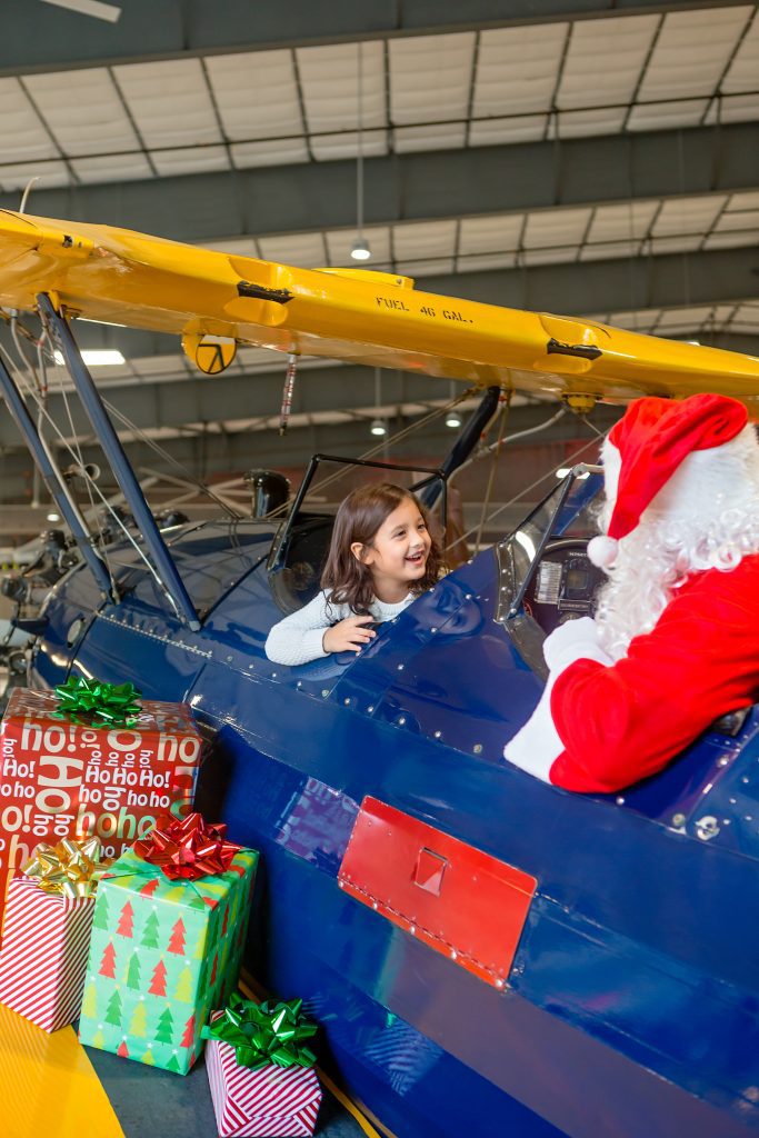 girl talks to Santa who is sitting in an airplane