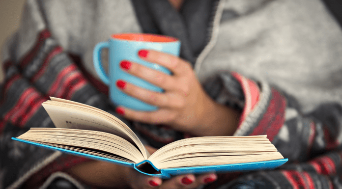 woman with coffee in hand reads a book